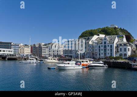 Boote auf dem Kanal in Alesund, Norwegen; auf dem Hügel auf der rechten Seite ein Aussichtspunkt mit Blick auf die Stadt. Stockfoto