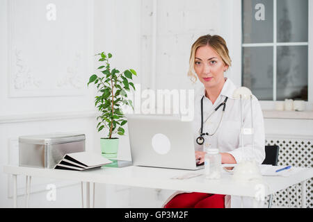 Porträt der jungen Frau Doktor mit Stethoskop im weißen Kittel am computer Stockfoto