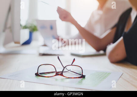 Business-Team diskutieren in der Nähe von Computer, Fokus auf Gläser im Vordergrund Stockfoto