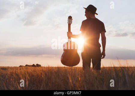 Silhouette der Musiker mit Gitarre bei Sonnenuntergang Feld Stockfoto