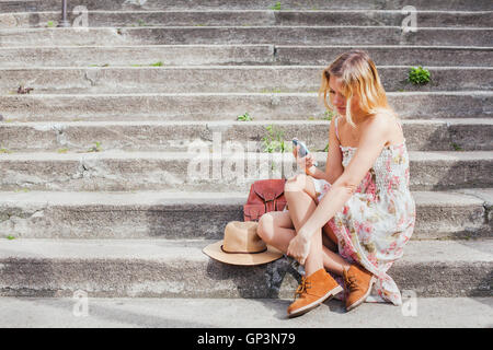 SMS auf Handy, Frau mit Smartphone-app beim Sitzen auf der Treppe, soziales Netzwerk Stockfoto