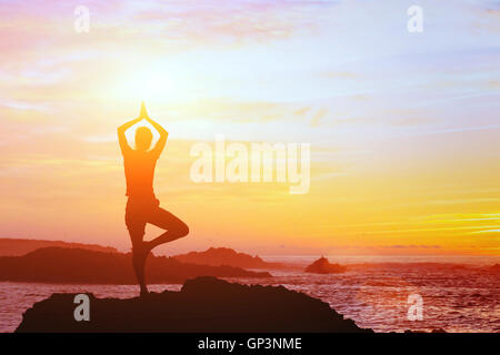 schöne Yoga Hintergrund, Silhouette der Frau am Strand bei Sonnenuntergang, Achtsamkeit Stockfoto