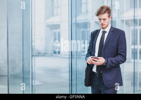 Geschäftsmann mit Smartphone in der Nähe von Bürogebäude Stockfoto