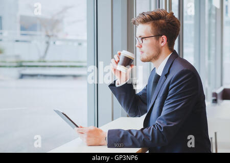 Business-Mann denken, Kaffee trinken und mit Blick auf das Fenster im modernen Café-Interieur Stockfoto