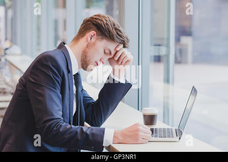 Kopfschmerzen, müde Geschäftsmann in der Nähe von laptop Stockfoto