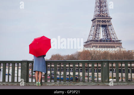 Frau mit roten Regenschirm stehen auf der Brücke mit Blick auf den Eiffelturm in Paris, Frankreich Stockfoto