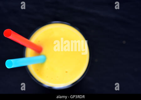 Mango Lassi auf Blacck Hintergrund. Mango-Smoothie mit Mango und Joghurt, Joghurt gemacht. Selektiven Fokus. Ansicht von oben. Kopieren Sie Raum. Stockfoto