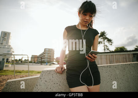 Porträt einer schönen und sportlichen jungen Frau anhören von Musik mit einer Pause nach im freien laufen. Stockfoto