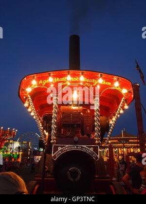 Dies ist die Vorderseite des einen Showmans Dampftraktor durch einen eigenen Generator und Glühbirnen, Kirmes im Hintergrund beleuchtet Stockfoto