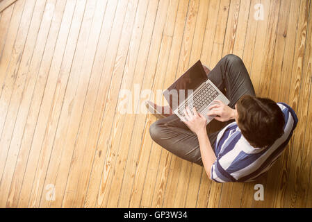 Mann, sitzend indischen Stil Erdgeschoss mit Laptop-computer Stockfoto