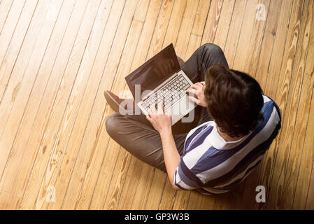 Mann, sitzend indischen Stil Erdgeschoss mit Laptop-computer Stockfoto