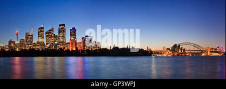 Panorama der Stadt Sydney CBD und Sehenswürdigkeiten rund um Hafen Harbour Bridge und North Sydney. Beleuchtete Gebäude reflektieren Stockfoto