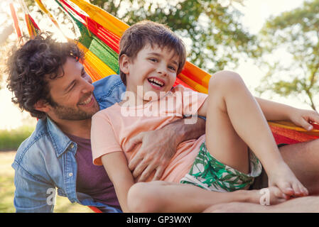 Vater und Sohn gemeinsam in der Hängematte entspannen Stockfoto