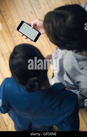 Mann zeigt Begleiter wie Sie e-Mails auf smartphone Stockfoto