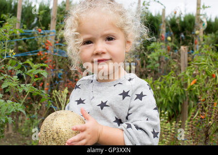 Kleines Mädchen mit Melone im Garten Stockfoto