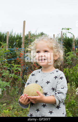 Kleines Mädchen mit Melone im Garten Stockfoto