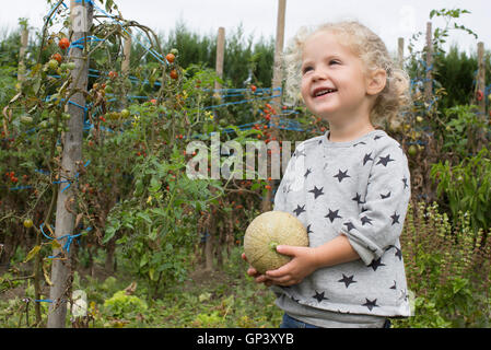 Kleines Mädchen mit Melone im Garten Stockfoto