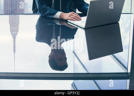 Geschäftsmann mit Laptop-Computer, Reflexion über Top Glastisch Stockfoto