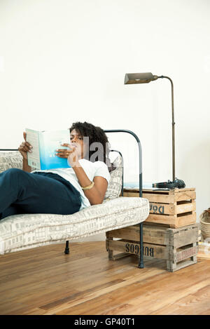 Frau liegt auf dem Sofa lesen Buch Stockfoto