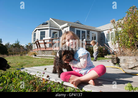 Kleines Mädchen sitzt auf dem Deck mit Hund