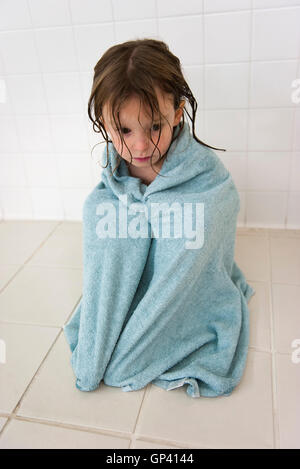 Kleines Mädchen in ein Handtuch gewickelt und blickte traurig Stockfoto