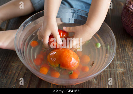 Kind waschen Tomaten Stockfoto