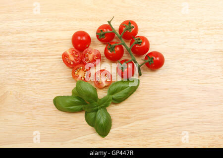 Rebstock gereift, Tomaten und Basilikum auf ein Schneidbrett aus Holz Stockfoto