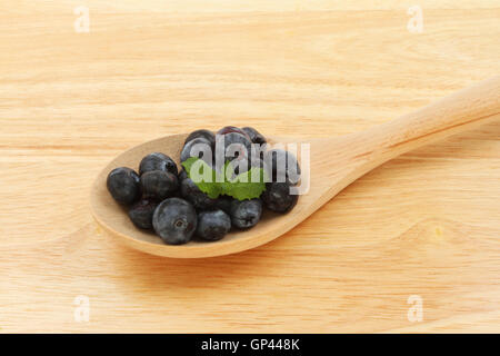 Blaubeeren und Minze Blätter in einem Holzlöffel auf ein Schneidbrett aus Holz Stockfoto