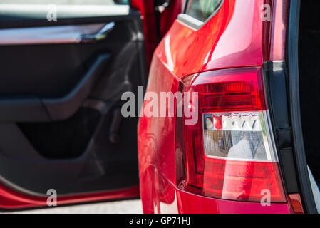 Nahaufnahme eines hinteren Autos Licht. Rotes Auto mit offenen Seitentür und Stamm. Stockfoto