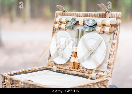 Nahaufnahme von einem offenen Picknick-Korb über Holztisch im Park. Stockfoto