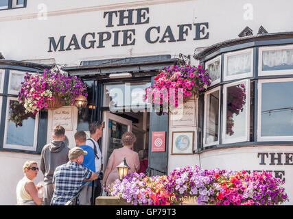 Menschen Schlange, um an der berühmten Magpie Cafe am Strand von Whitby in North Yorkshire serviert bekommen Stockfoto