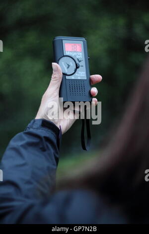 Eine Frau hält einen Fledermausdetektor auf geführte Fledermaus Identifikation Abendspaziergang in Derbyshire, England UK - Sommer Modell veröffentlicht Stockfoto