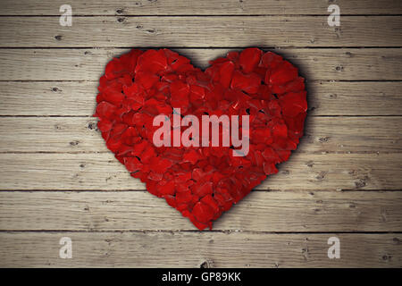 Rosenblätter in Form von Herzen auf Holztisch angeordnet. Stockfoto