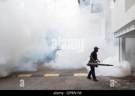 Ein Arbeiter Nebel gegen Mücken um eine Eigentumswohnung in Kuala Lumpur, Malaysia. Stockfoto