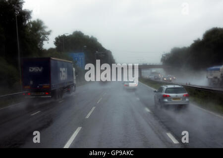 Fahrt auf der mittleren Spur auf UK-Autobahn bei Armen Nässe umgeben von LKW und PKW Stockfoto