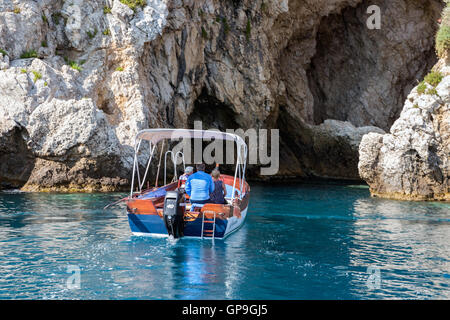 Motorboot mit Menschen in einer Höhle an der felsigen Küste von Taormina am 21. Mai 2016 auf der Insel Sizilien, Italien Stockfoto