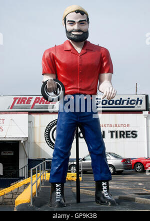 Der Schalldämpfer hält einen Reifen und steht hoch in Atlanta, Georgia, einem klassischen Riesen am Straßenrand, der die Vintage-Americana und die Autokultur symbolisiert. Stockfoto