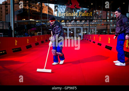 Ein Arbeiter kehren den roten Teppich vor dem Potsdamer Platz Theater in Berlin, Deutschland. Stockfoto