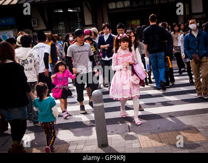 Eine Harajuku Mädchen überquert die Straße vor dem Bahnhof in Tokio, Japan Stockfoto