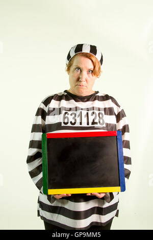 Reife Frau im Gefängnis einheitliche holding Tafel auf weißem Hintergrund. Stockfoto