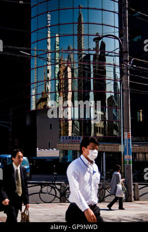 Fußgänger gehen vorbei an Gebäuden reflektiert in einem Bürohaus Fassade in Tokio, Japan. Stockfoto