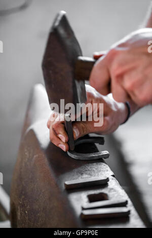 Schmied schmiedet ein Hufeisen. Glühenden Stahl hämmern. Stockfoto