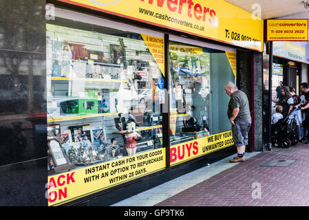 Menschen suchen im Fenster ein Cash Converters-Shop. Stockfoto