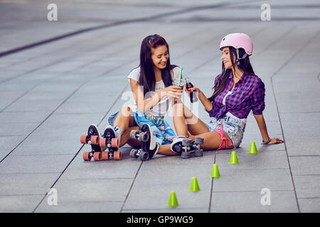 Zwei Mädchen auf Rollschuhen ausruhen und trinken Limonade Stockfoto