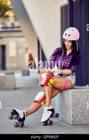 Schönes Mädchen setzt auf Schutzbekleidung für Inline-Skating Stockfoto