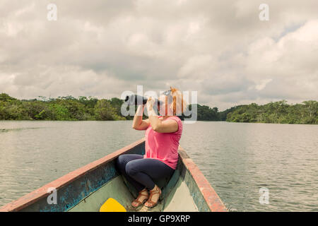Glücklich Blonde Frau mit Hochleistungs-Fernglas im Amazonas-Dschungel, Cuyabeno Nationalpark, Südamerika Stockfoto