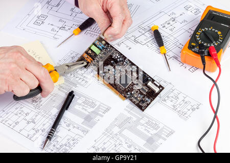 Elektroniker mit langer Nase Plires, eine Schnittstelle-Platte auf eine Computer-Karte zu sichern Stockfoto