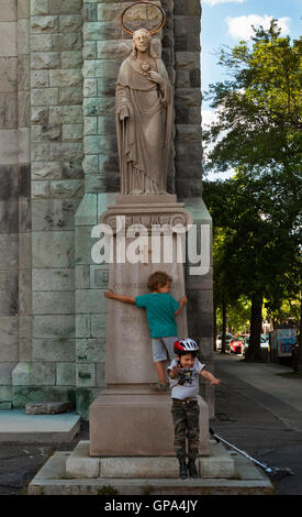 Kinder spielen vor der Statue von Christus vor einer Kirche, Montreal. Stockfoto