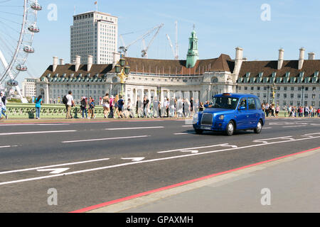 London, England - 31. August 2016: typische Londoner Taxi Westminster Brücke überquert. Im Hintergrund ist die alte County Hall Stockfoto