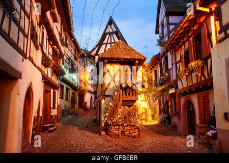 Traditionellen Fachwerkhäusern beleuchtet am Abend in Eguisheim von Colmar, Elsass, Frankreich Stockfoto